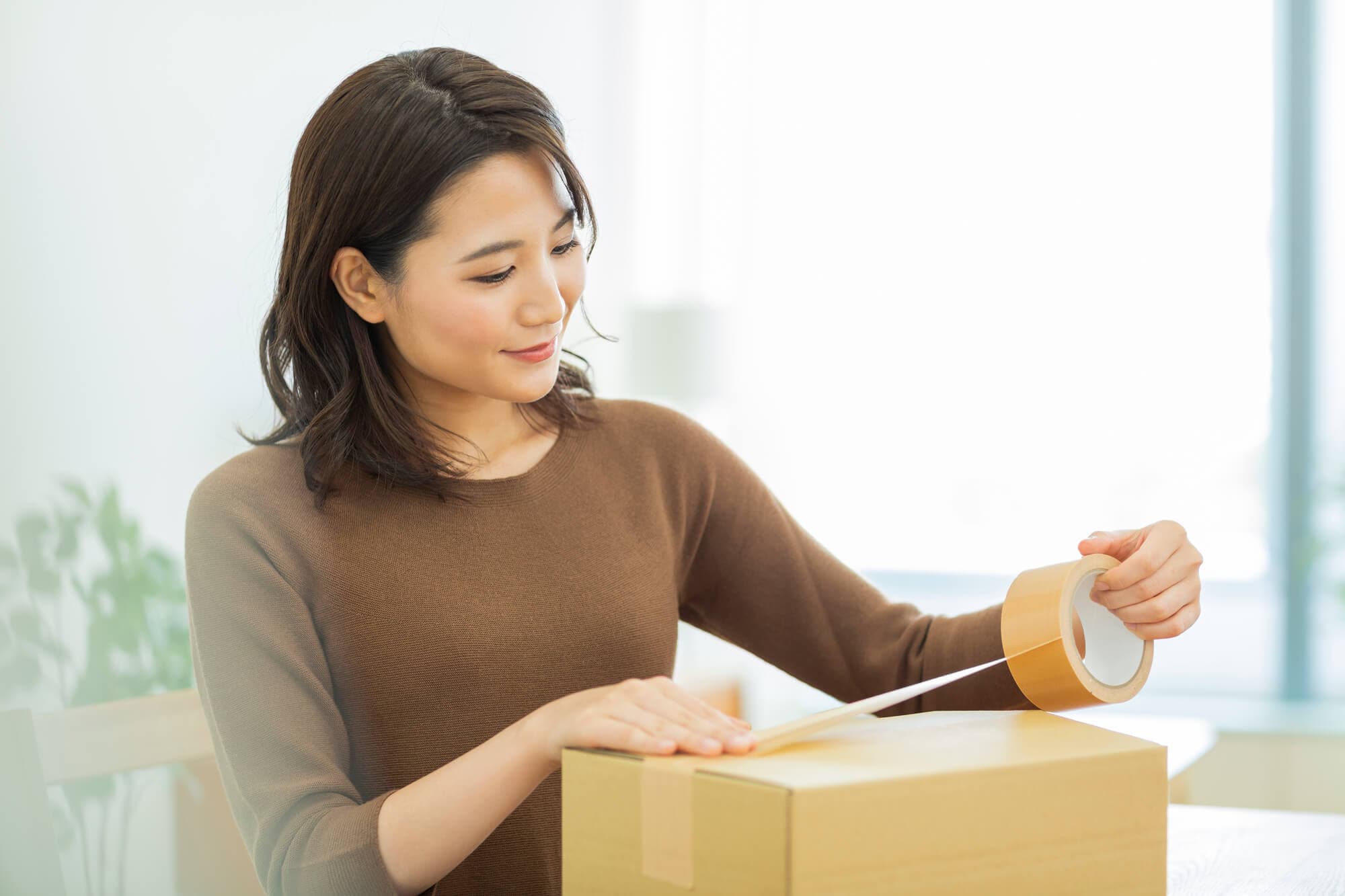段ボールを閉める女性