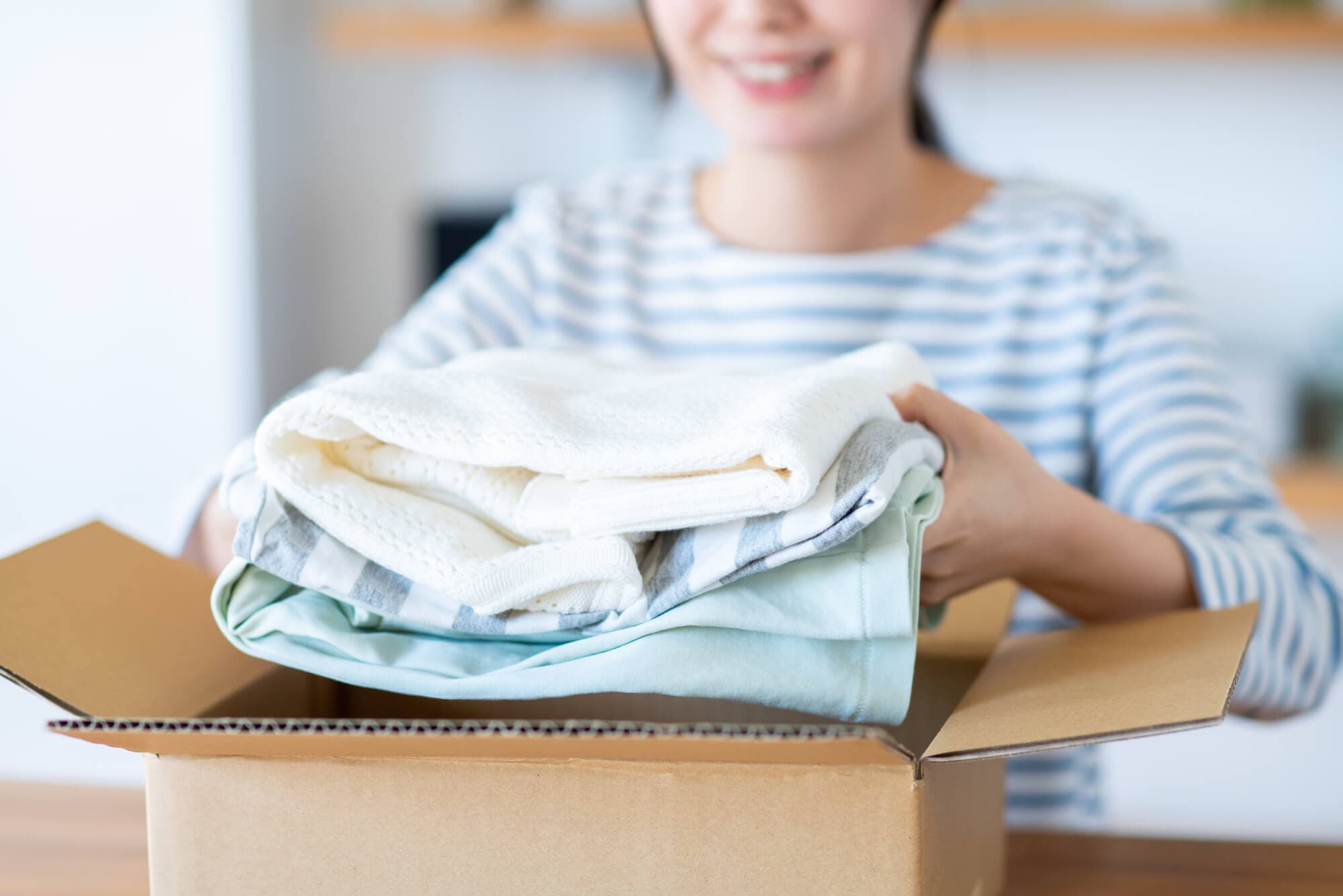 段ボールに服を詰める女性
